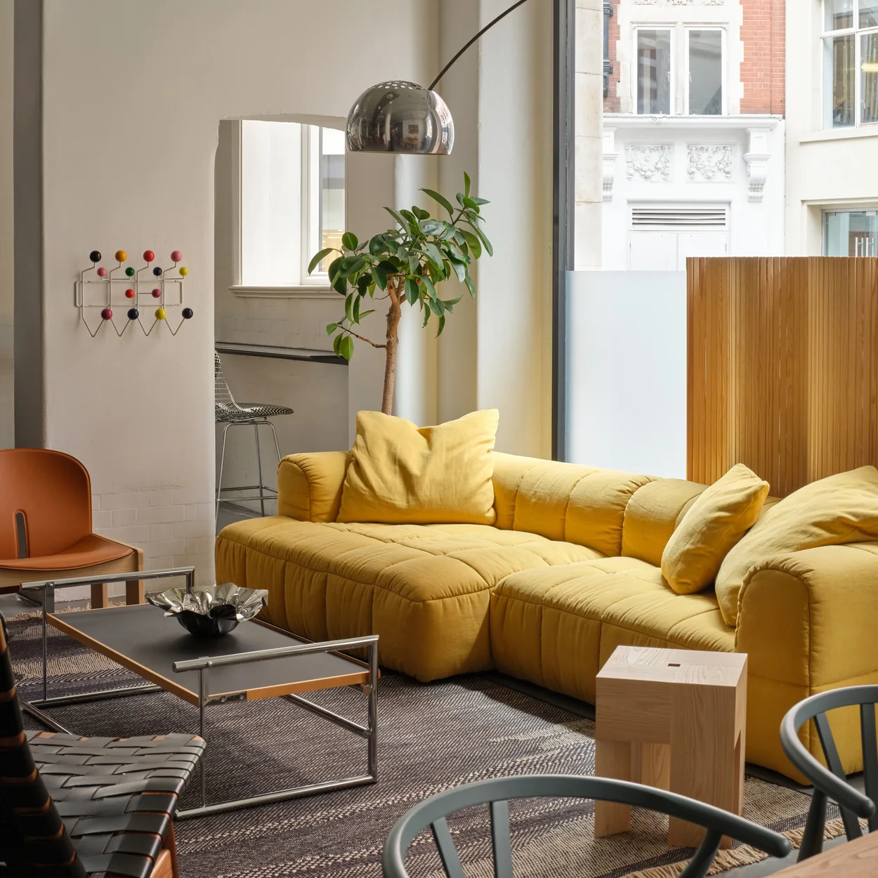 Aram display of a yellow sofa, arc floor lamp and design classics