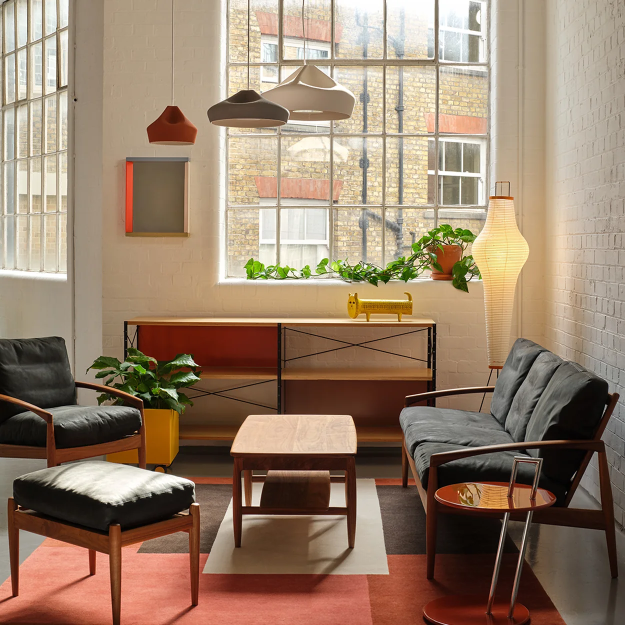 Aram room setting with lounge chairs, pendant lights and tall warehouse windows