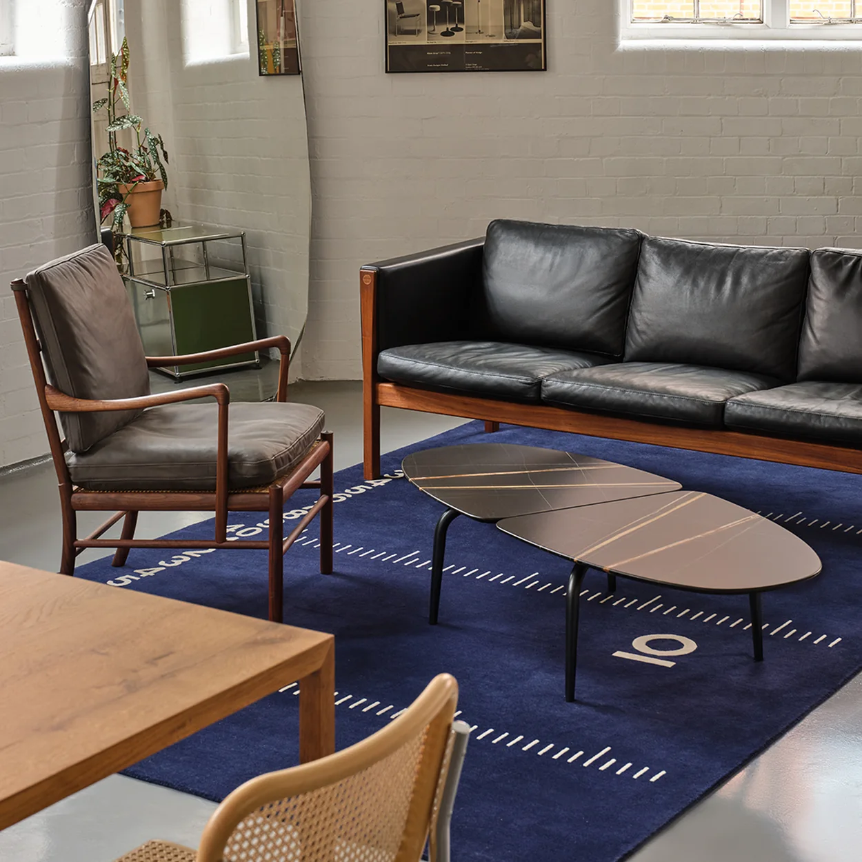 Aram display of leather seating, a dining table and a blue rug