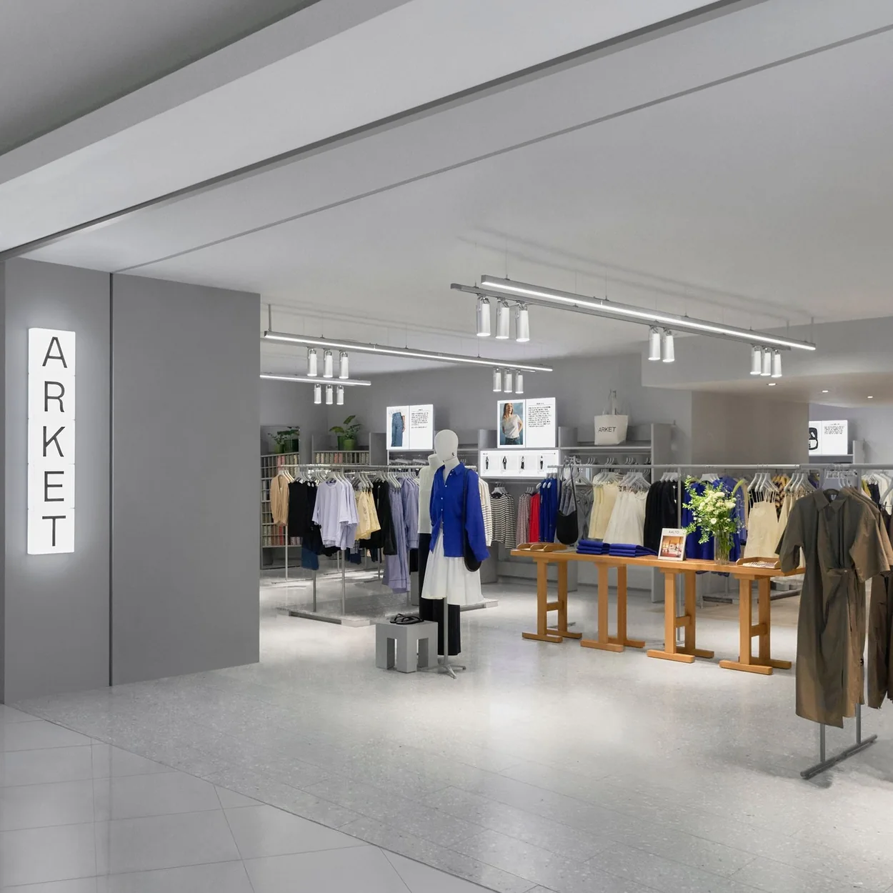 ARKET store interior with clothing rails and a wooden display table