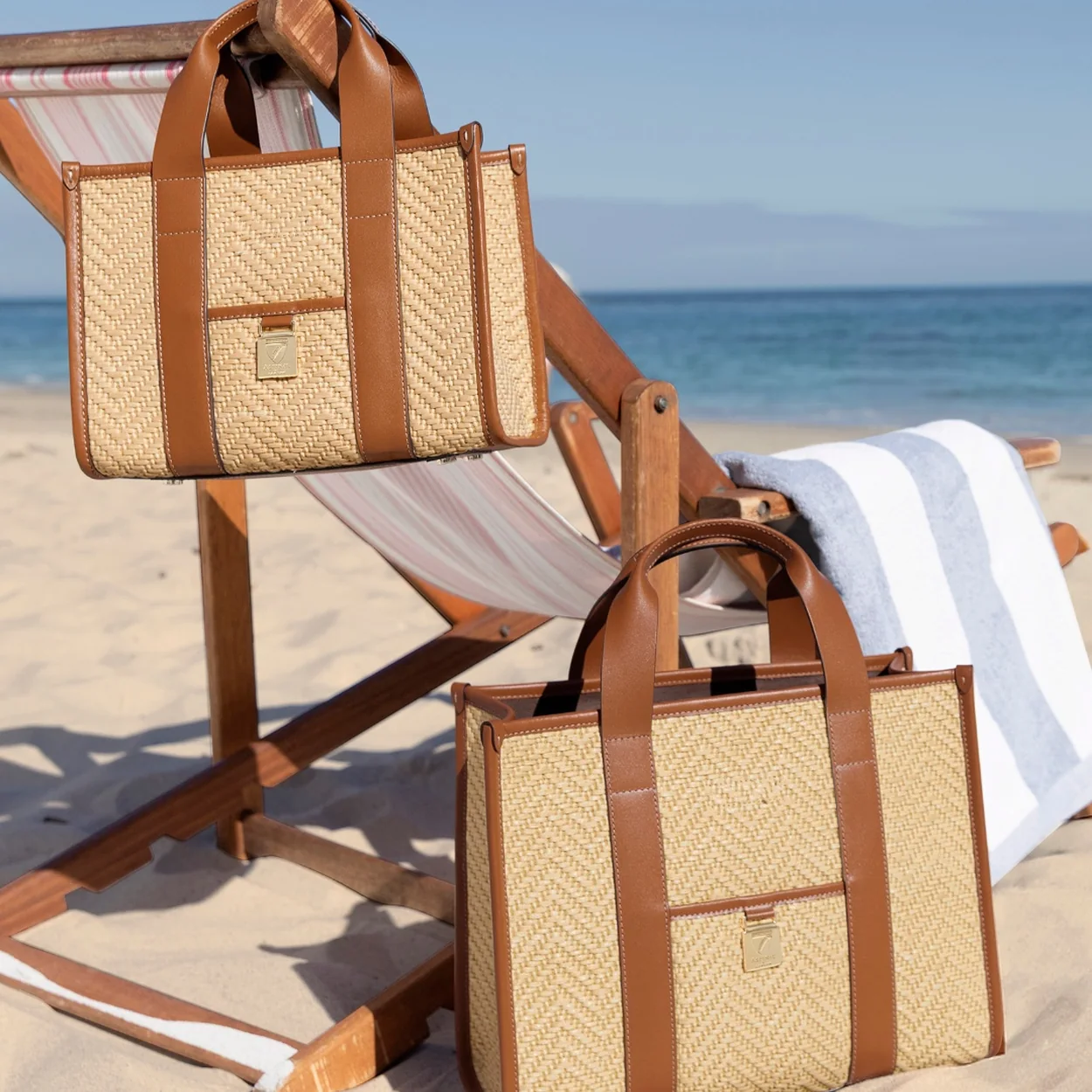Aspinal of London woven raffia and leather tote bags on a deckchair