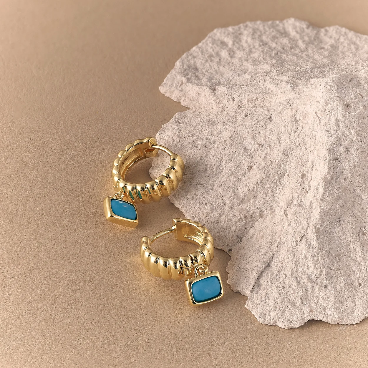 Astley Clarke gold rings with turquoise stones on white rock
