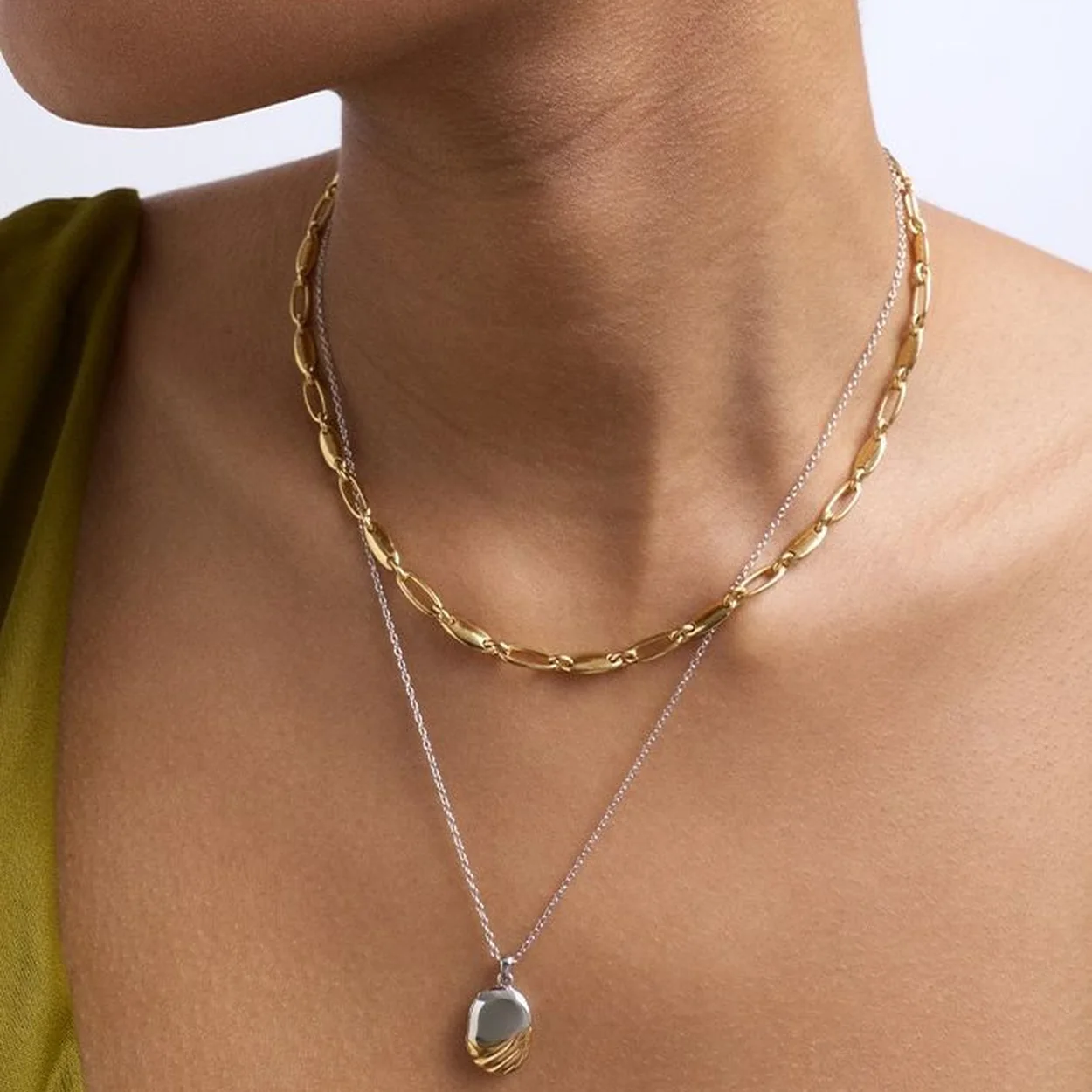 Astley Clarke layered gold chain necklaces and locket worn on the neck