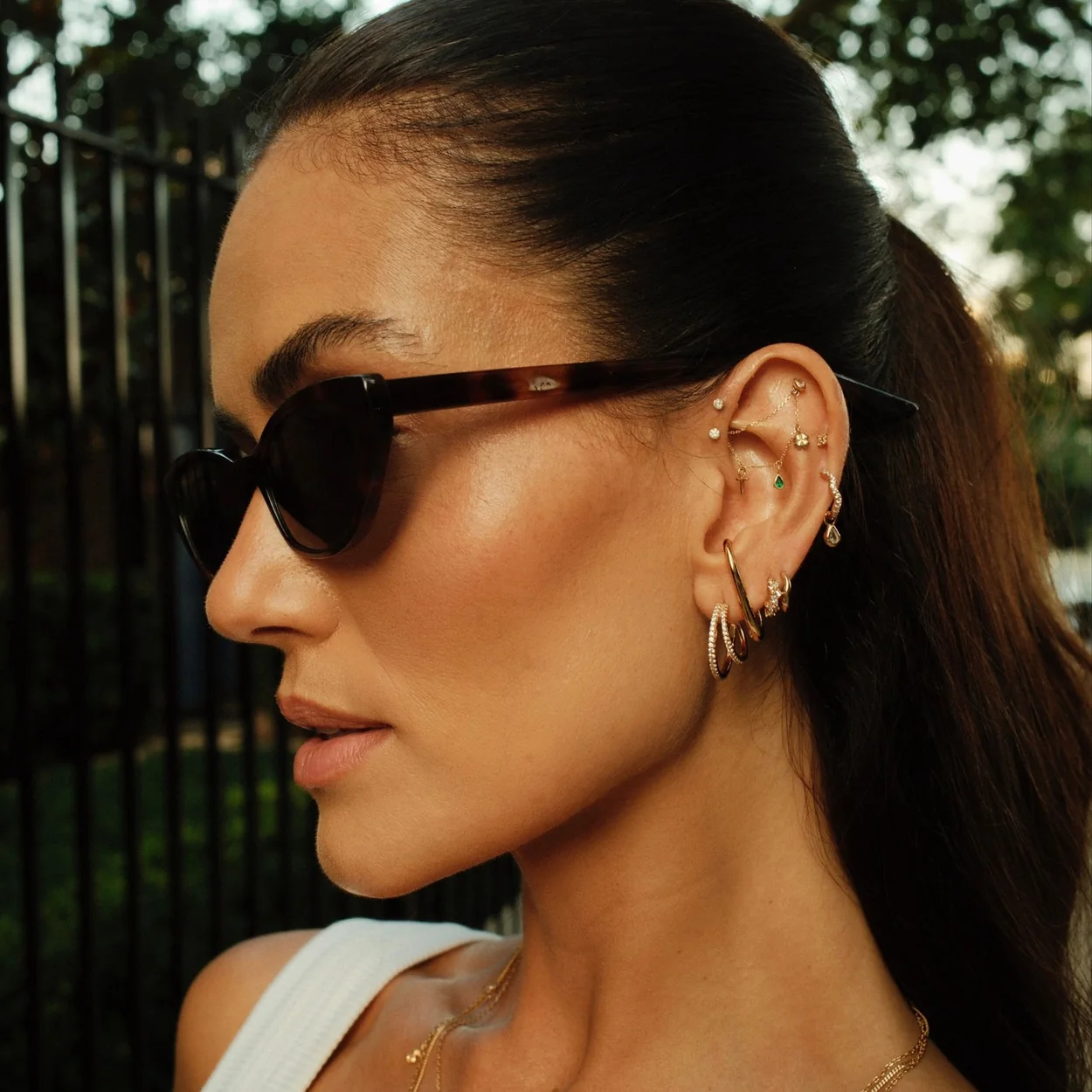 Astrid & Miyu layered gold earrings and necklace worn outdoors
