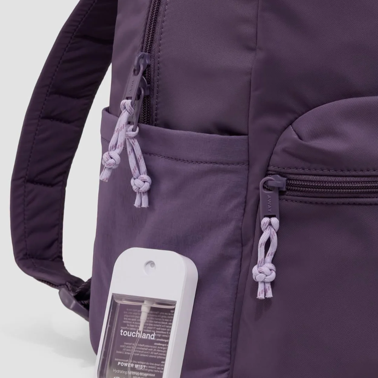 Away purple backpack showing front zip pocket and knotted pulls