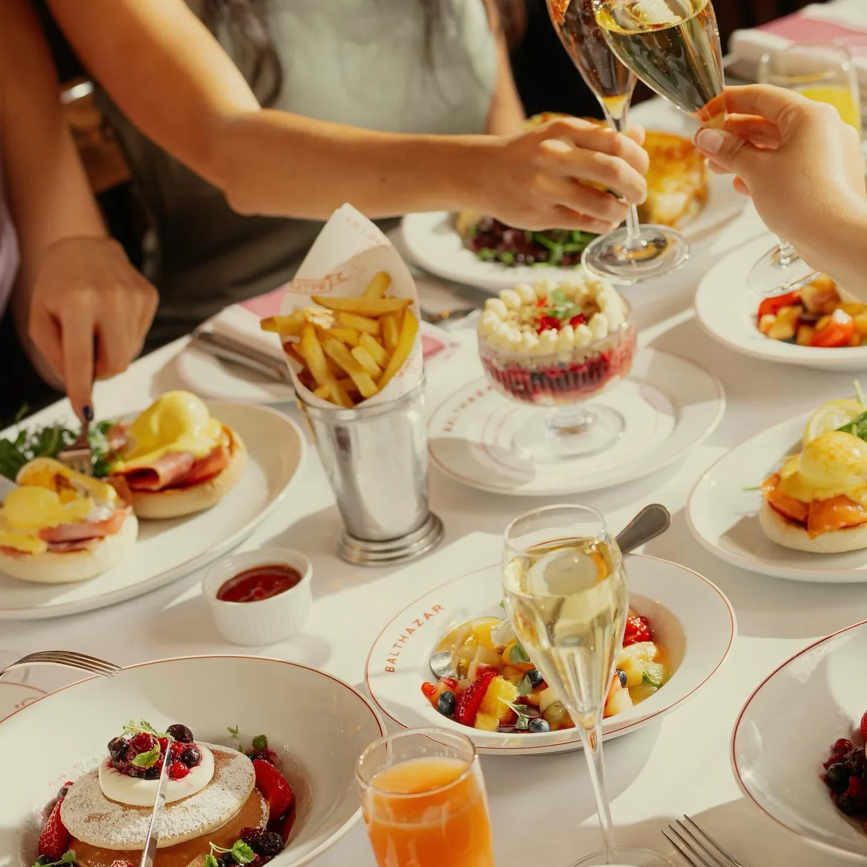 Balthazar weekend brunch table with eggs benedict, pavlova and cocktails