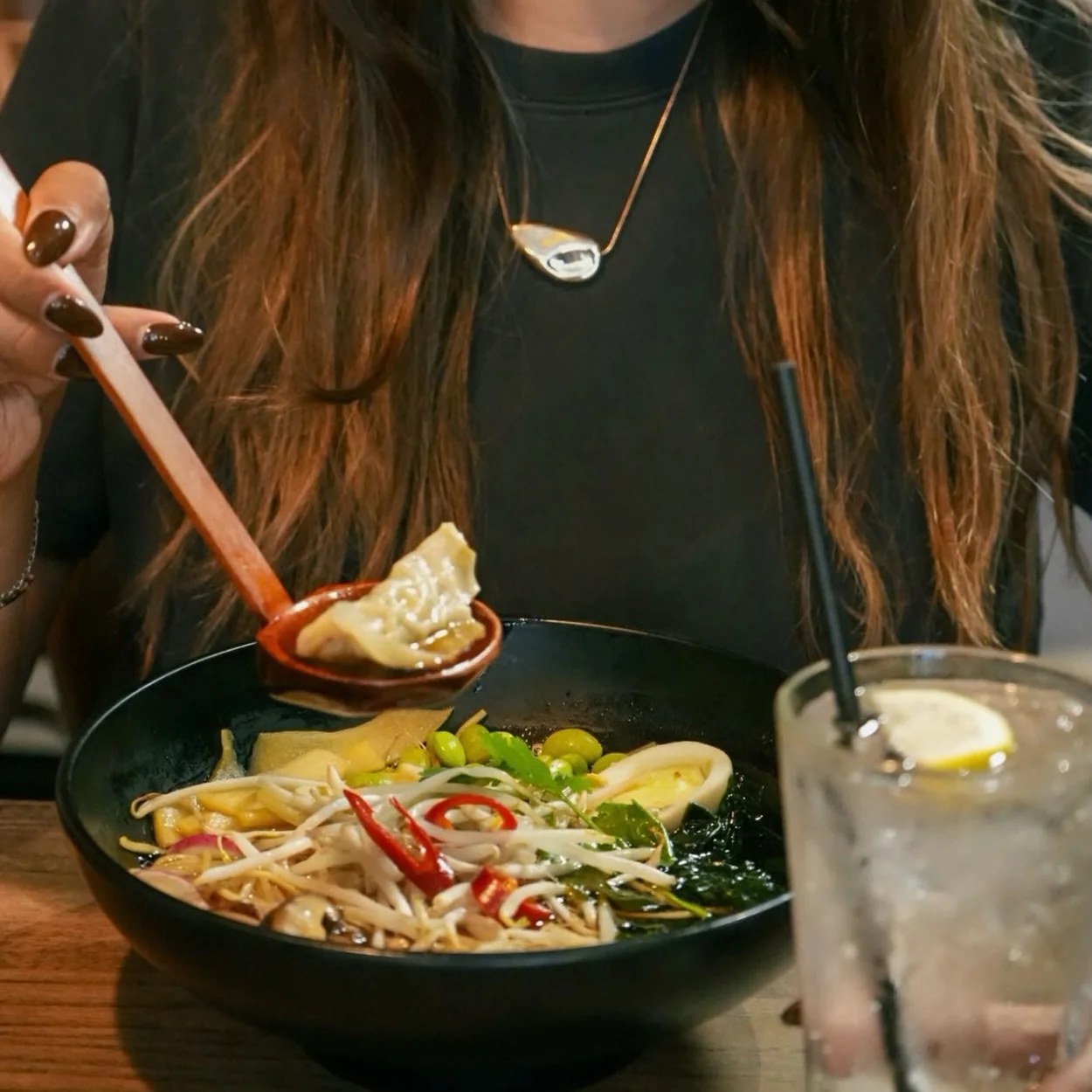 Banana Tree diner lifting dumplings from a noodle soup bowl