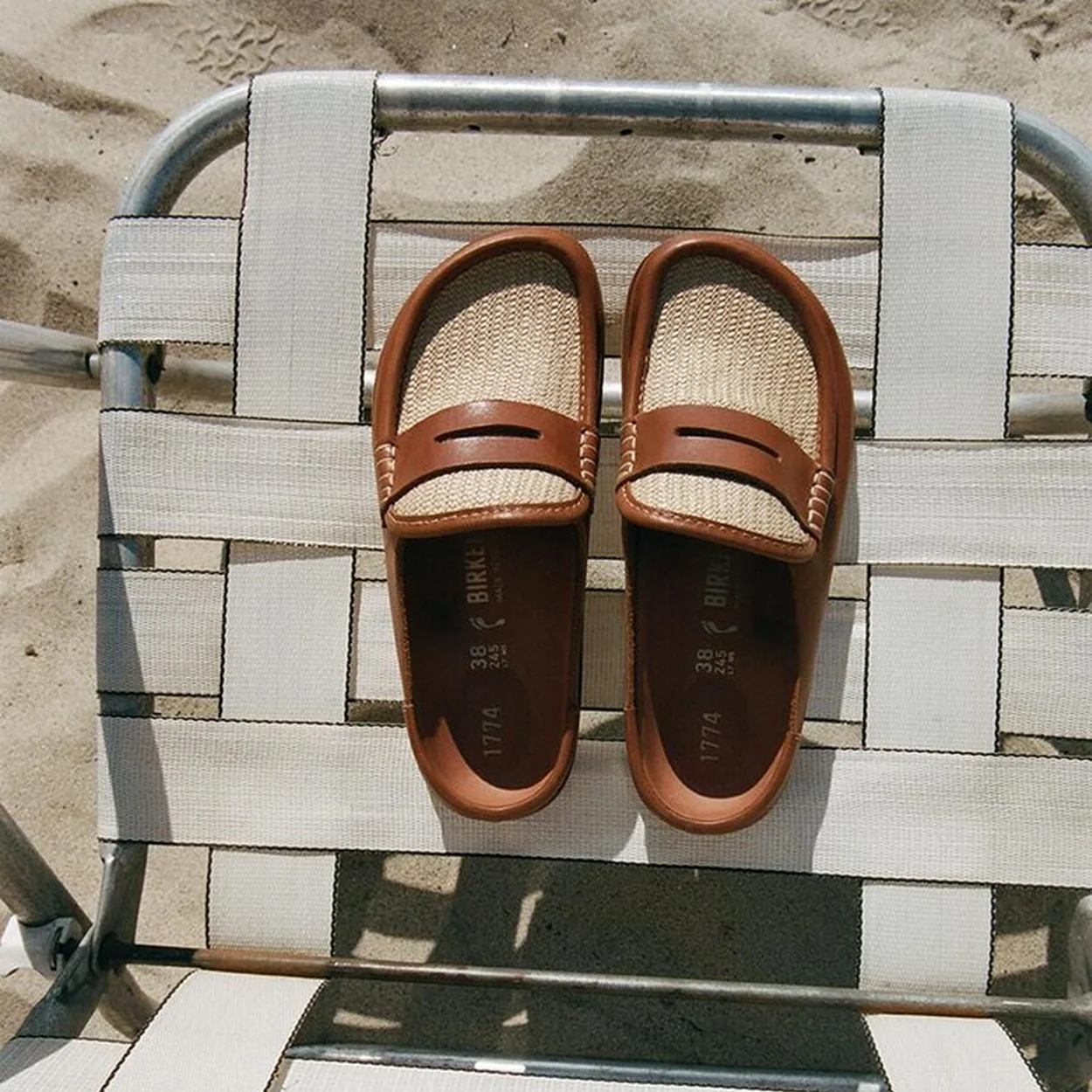 BIRKENSTOCK tan leather slip-on loafers on a woven chair
