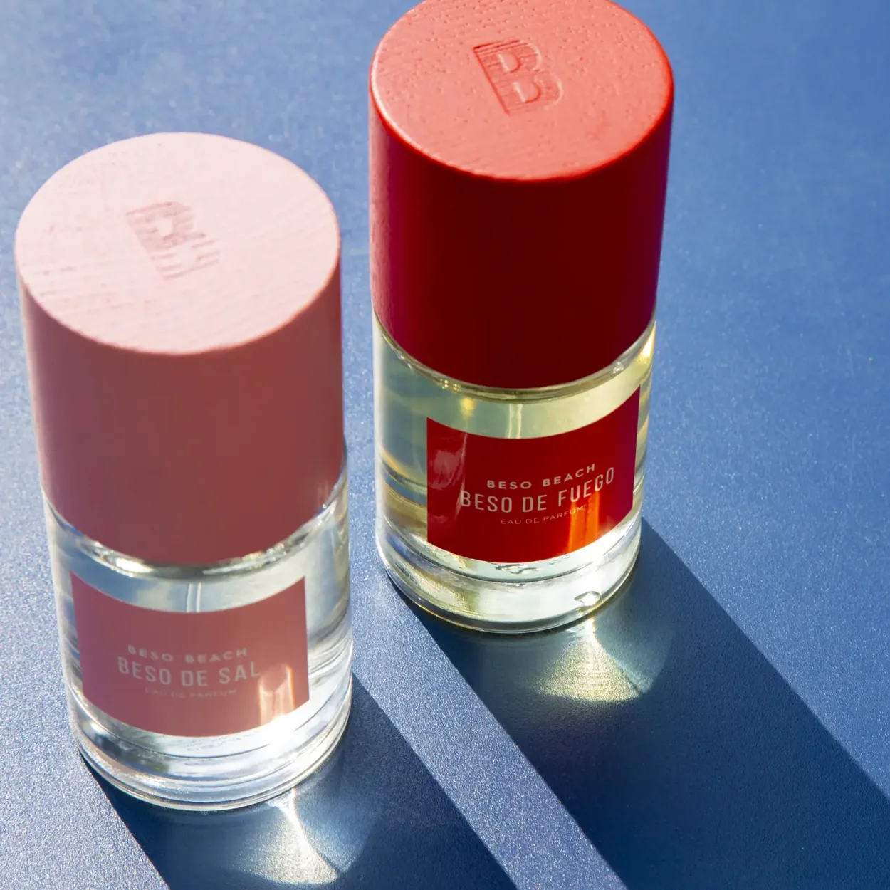 Bloom Perfumery Beso Beach fragrance bottles with red and pink caps