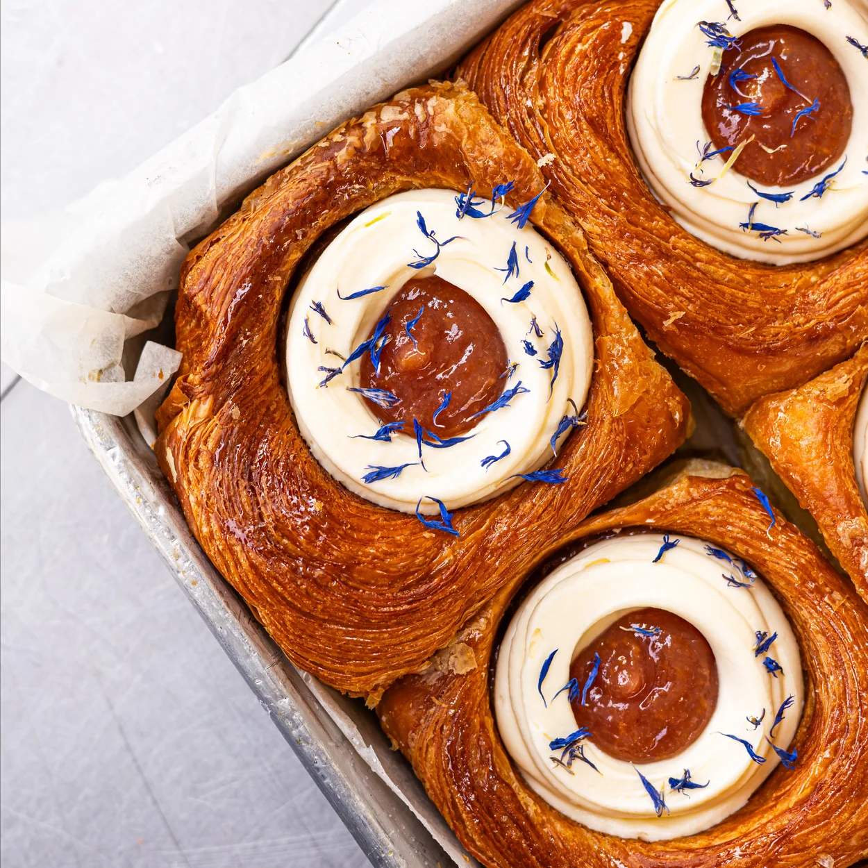 Buns From Home baked buns topped with cream and caramel on a baking tray