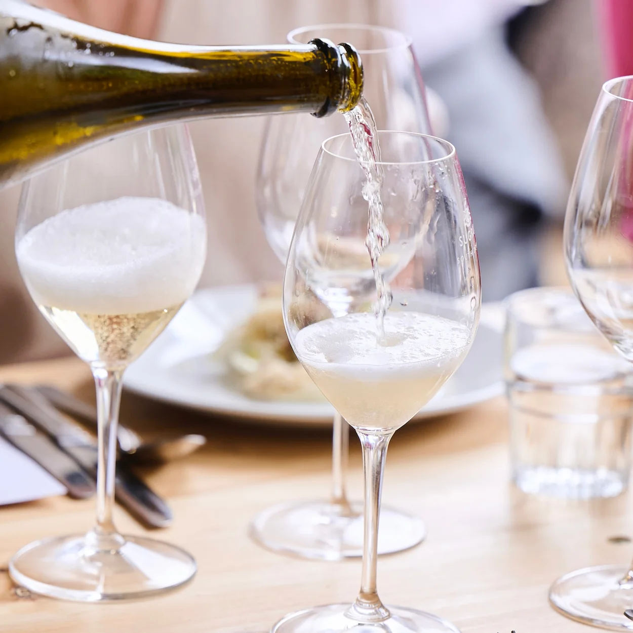 Café Murano white wine being poured at a laid table
