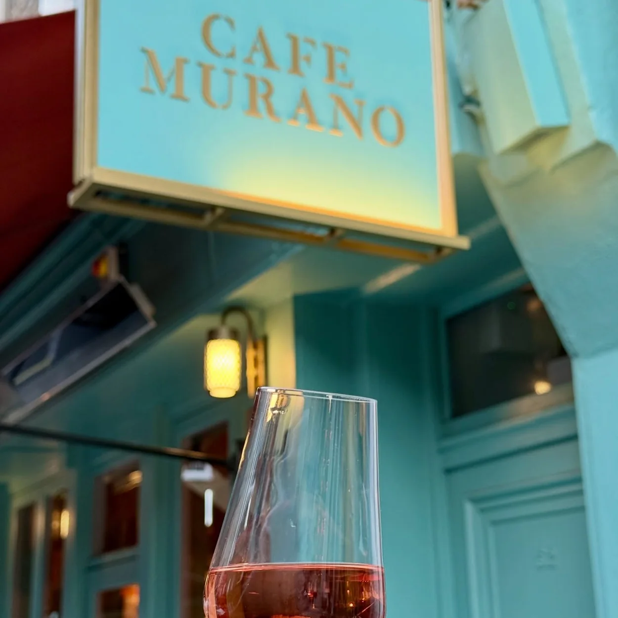 Café Murano sign above a glass of rosé outside the restaurant