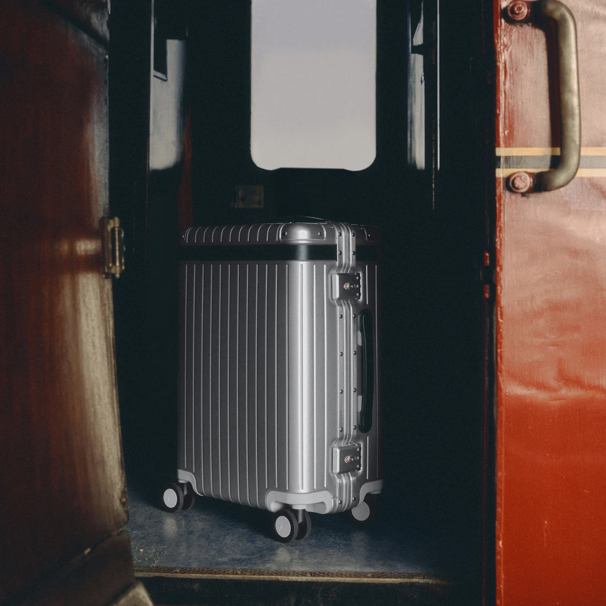Carl Friedrik aluminium carry-on case in a train carriage doorway