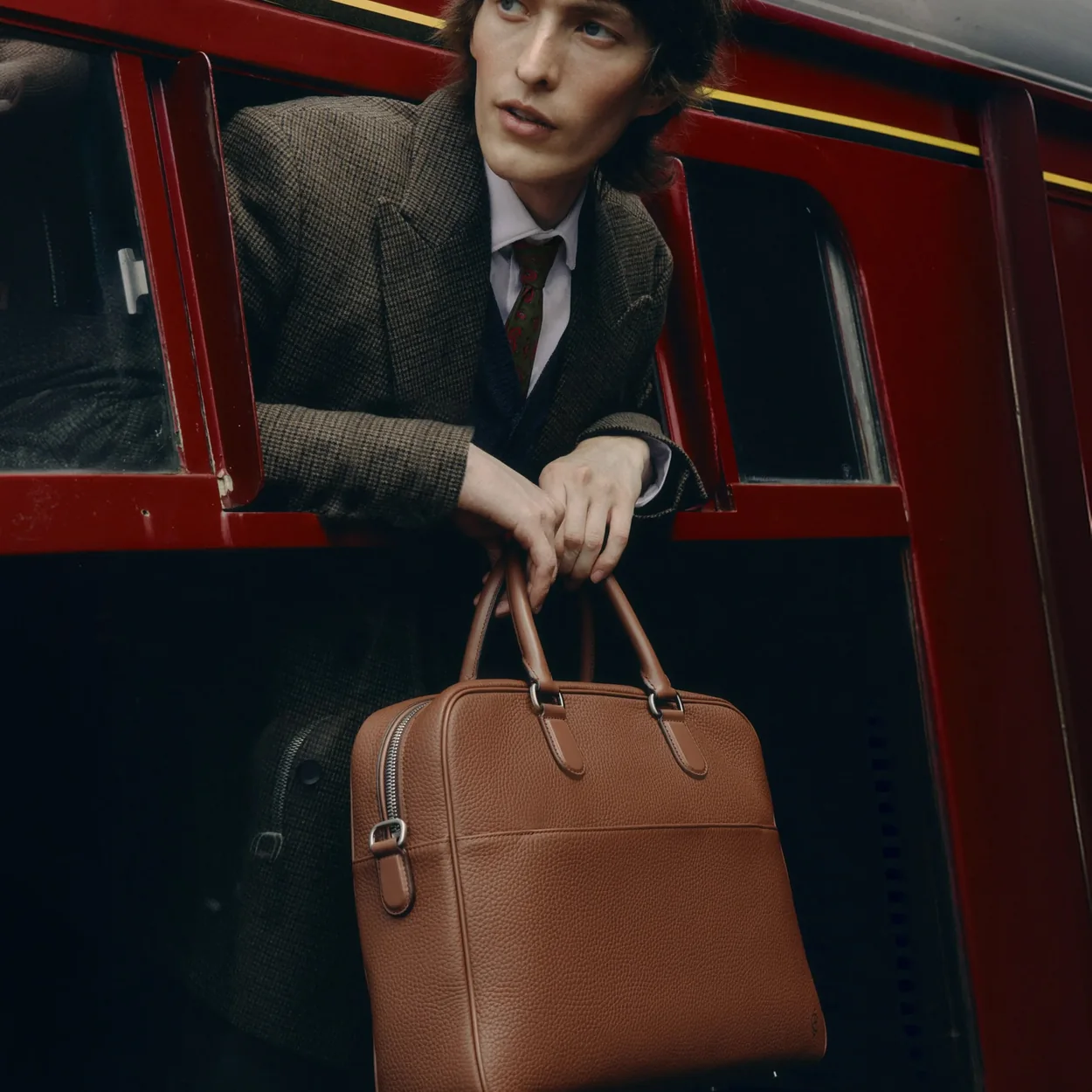 Carl Friedrik tan leather briefcase carried from a train window