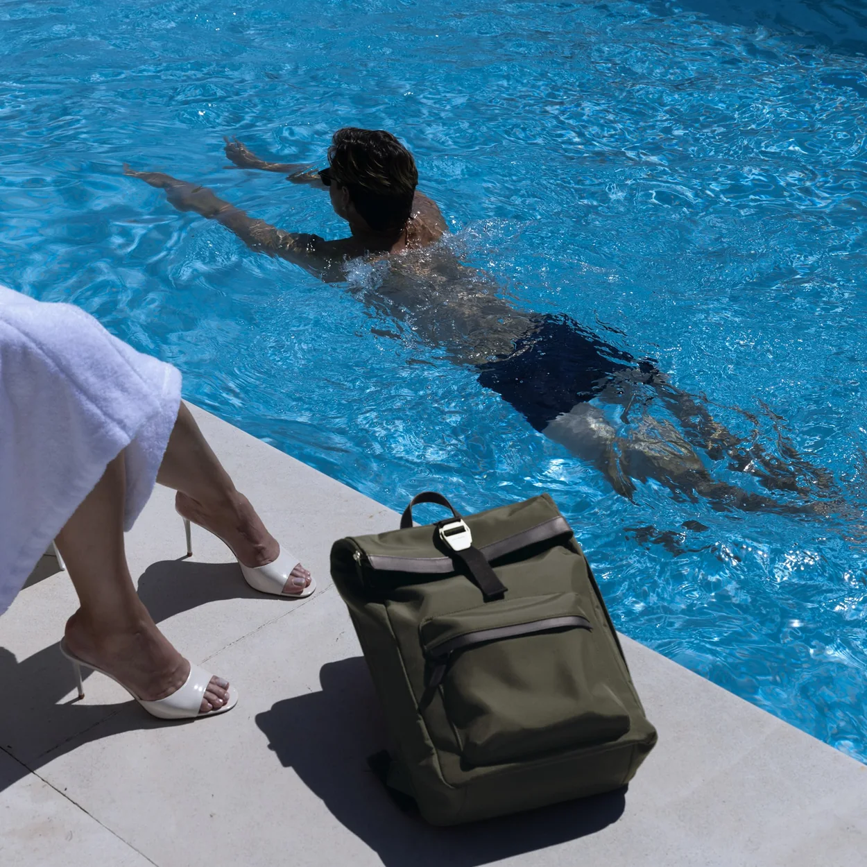Carl Friedrik olive leather backpack beside a swimming pool