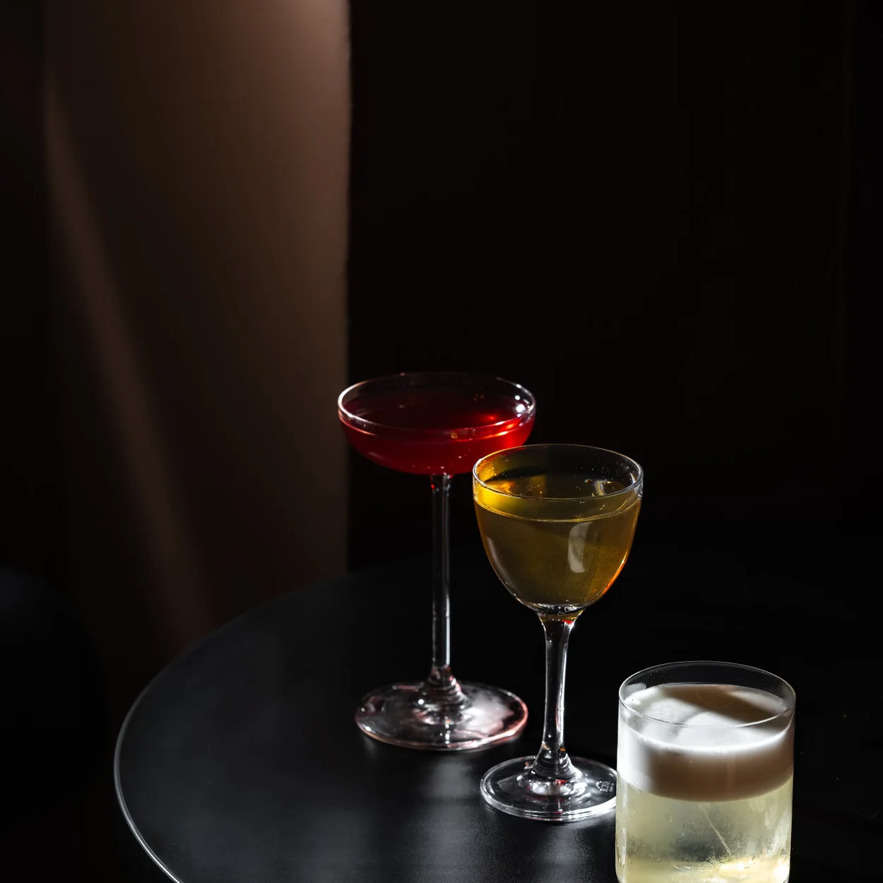 Cato cocktail bar, three house cocktails on a dark table