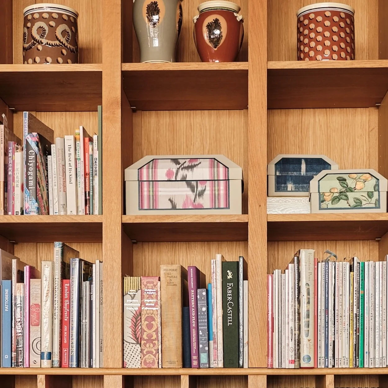 Choosing Keeping shelves of notebooks, ceramic pots and coloured paper