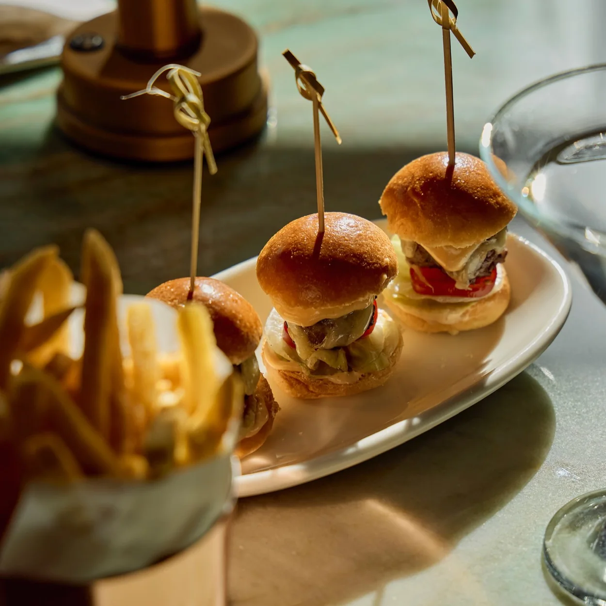 Christopher's mini burgers and fries served on a marble table