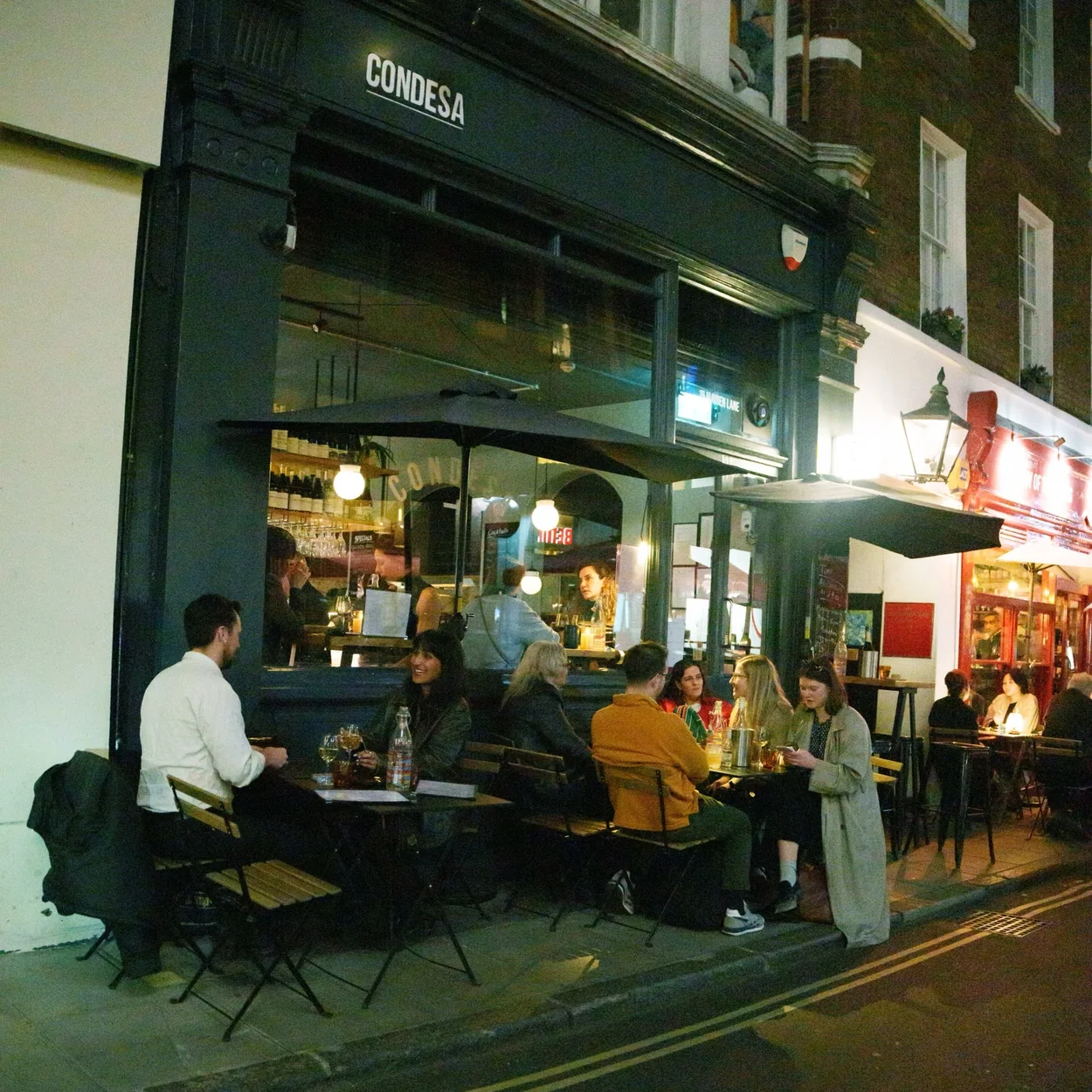 Condesa at night with diners at outdoor tables on Maiden Lane