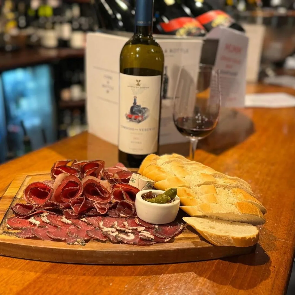 Cork & Bottle charcuterie board with bread and a bottle of wine at the bar