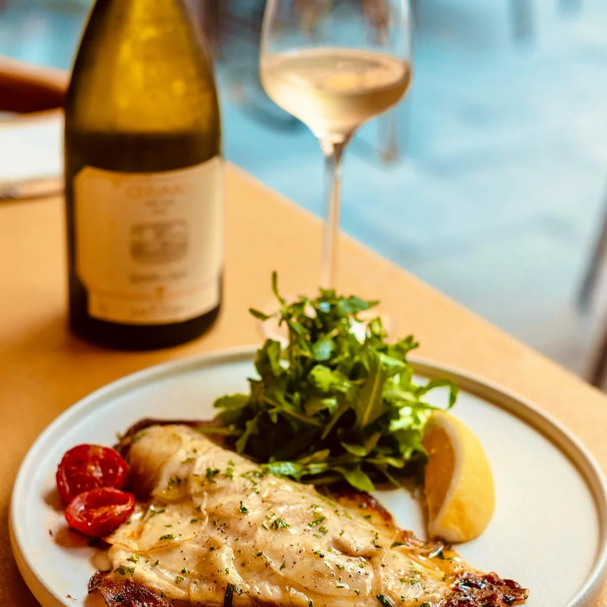 Dalla Terra grilled fish dish with rocket salad and a glass of white wine