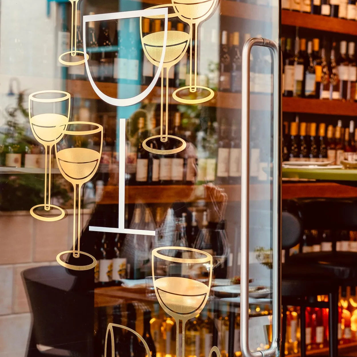 Dalla Terra window with painted wine glass motifs looking into the bar