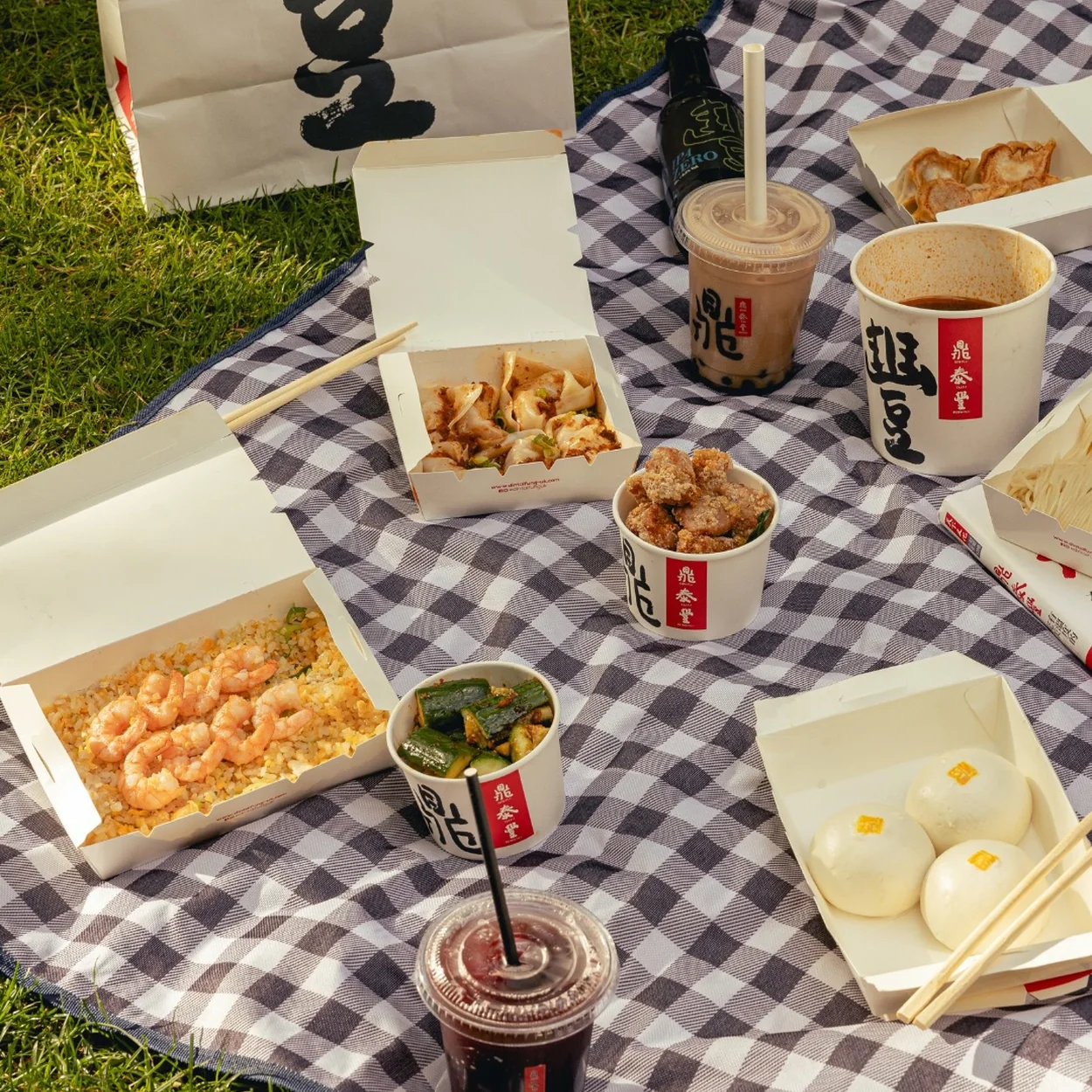 Din Tai Fung click and collect boxes and bubble tea laid out on a picnic blanket