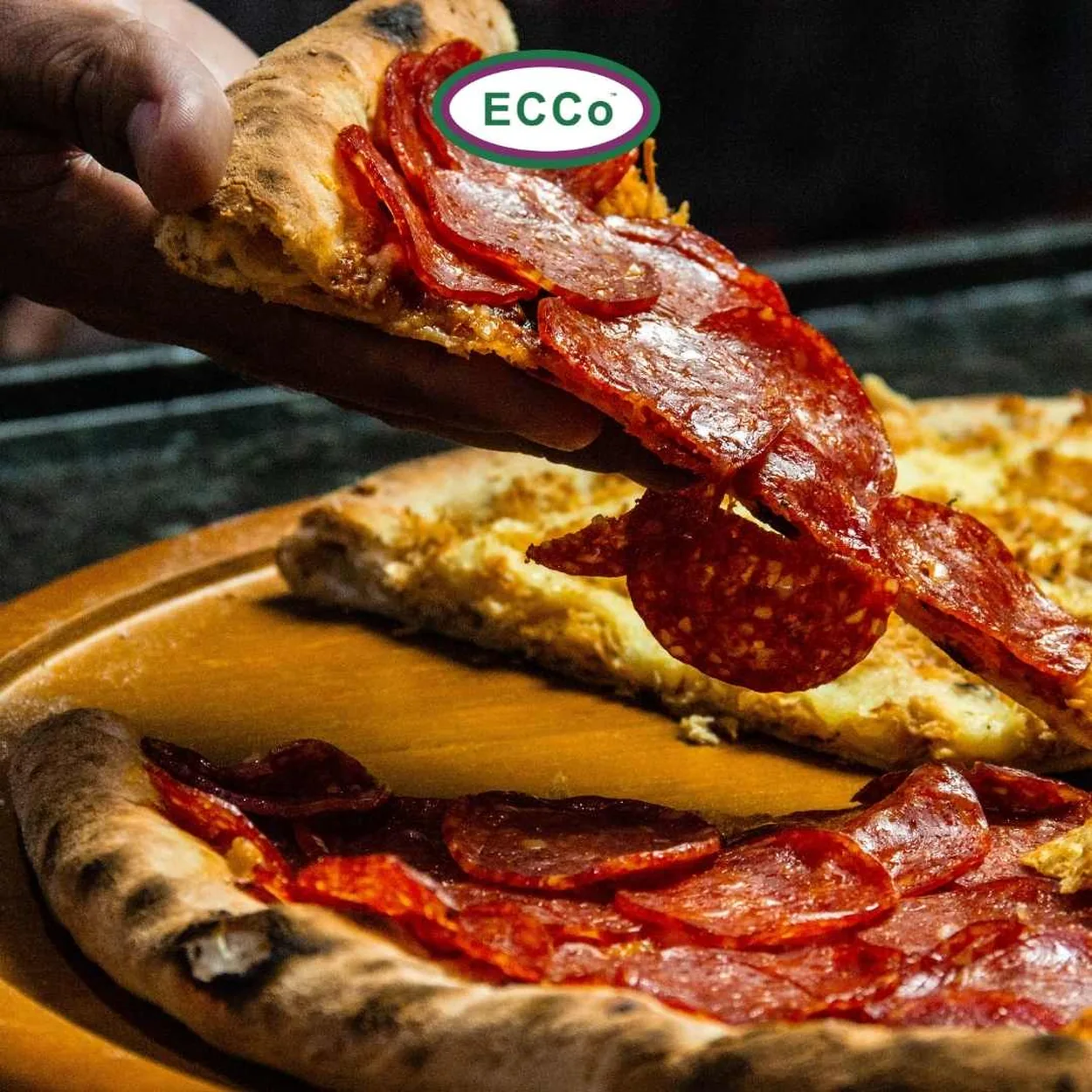 Ecco Pizza pepperoni slice lifted from a wooden board