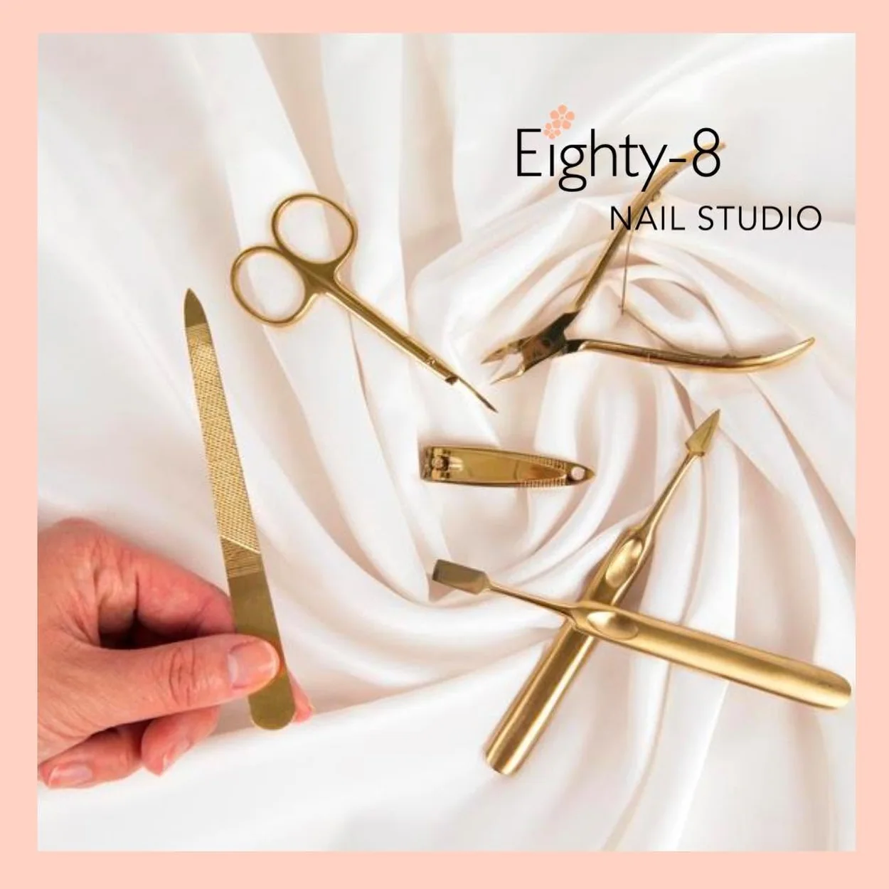 Eighty-8 Nail Studio gold manicure tools laid out on white satin