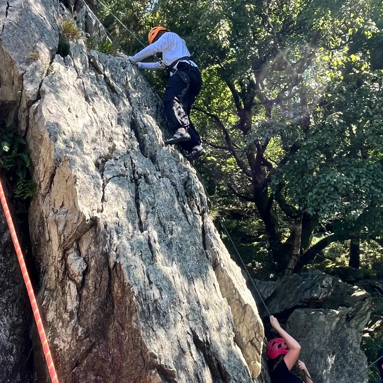 Ellis Brigham Mountain Sports climber on a rock face wearing a helmet and harness
