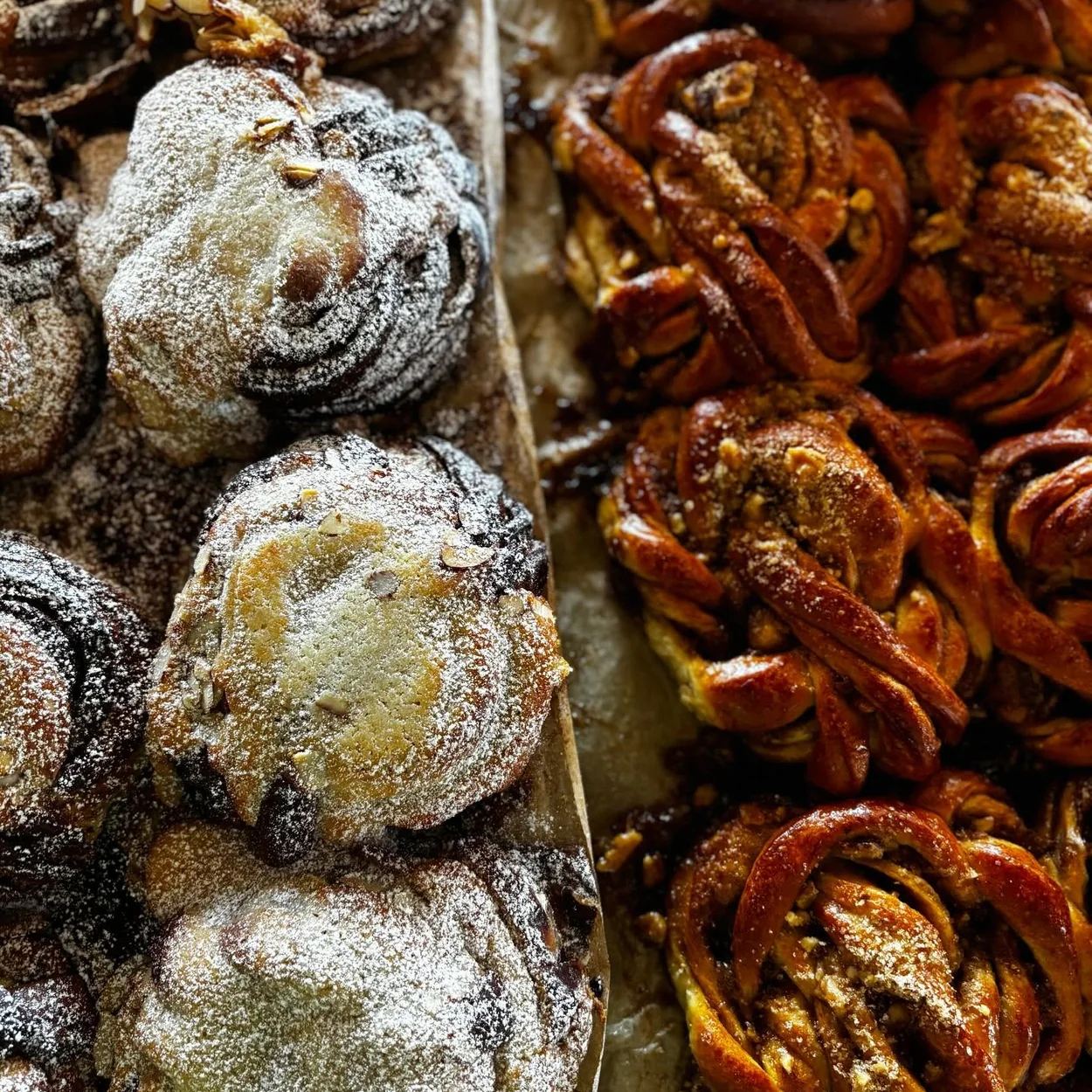 Fabrique pastries dusted with icing sugar beside cinnamon buns