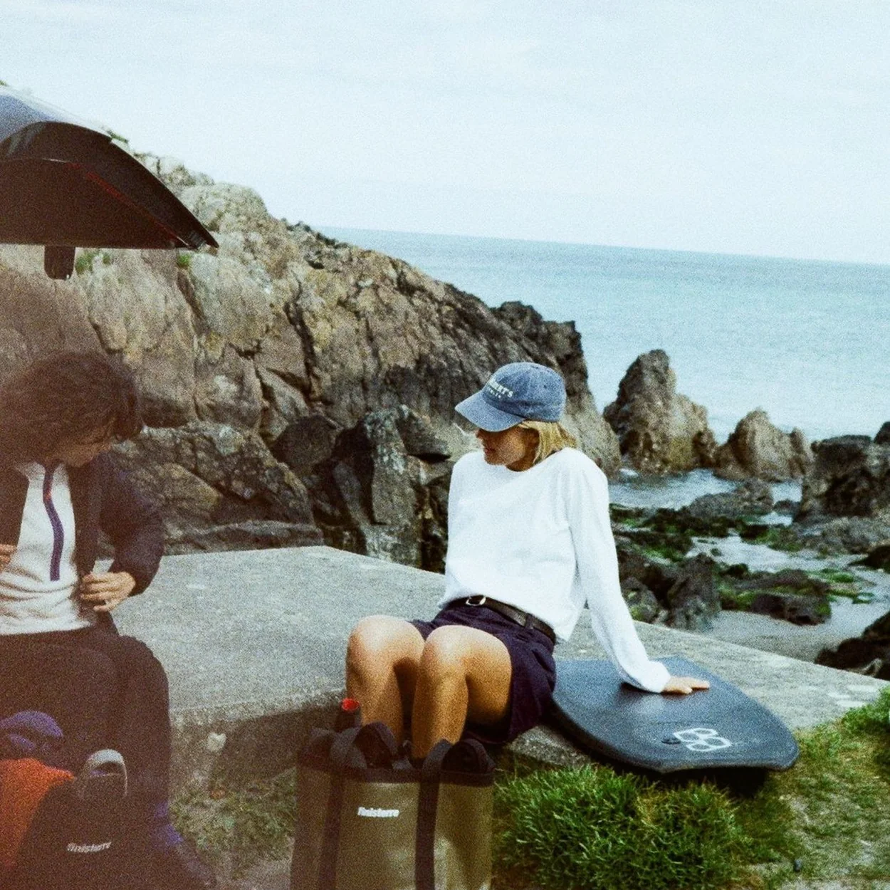 Finisterre tote bag and white shirt by rocks at the coast