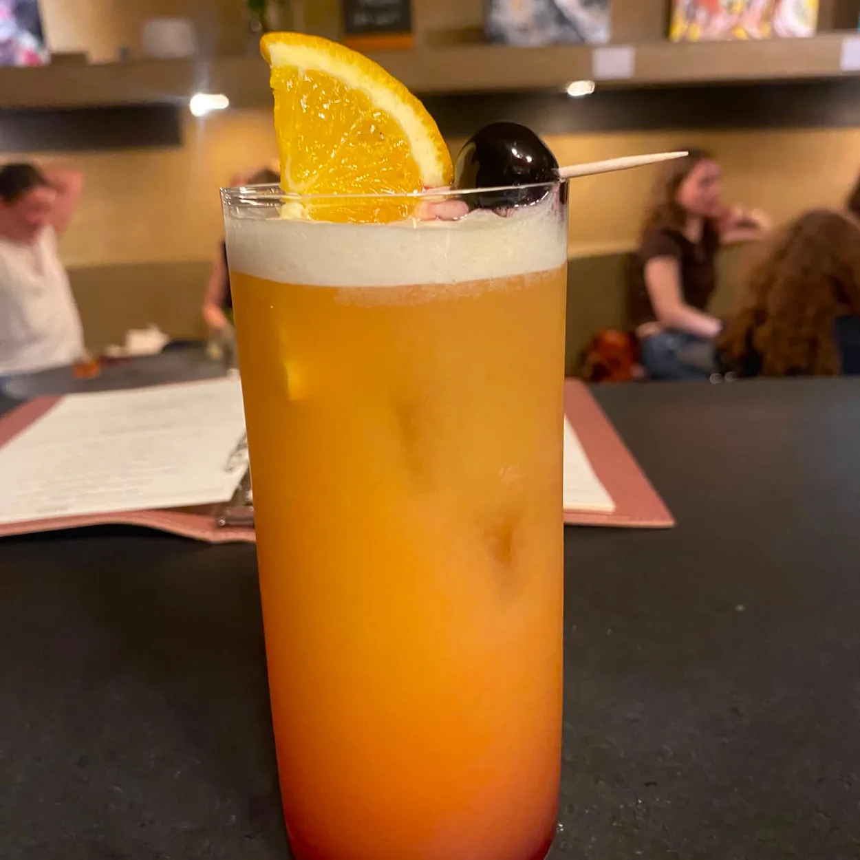 Freud tall orange cocktail with an orange slice garnish