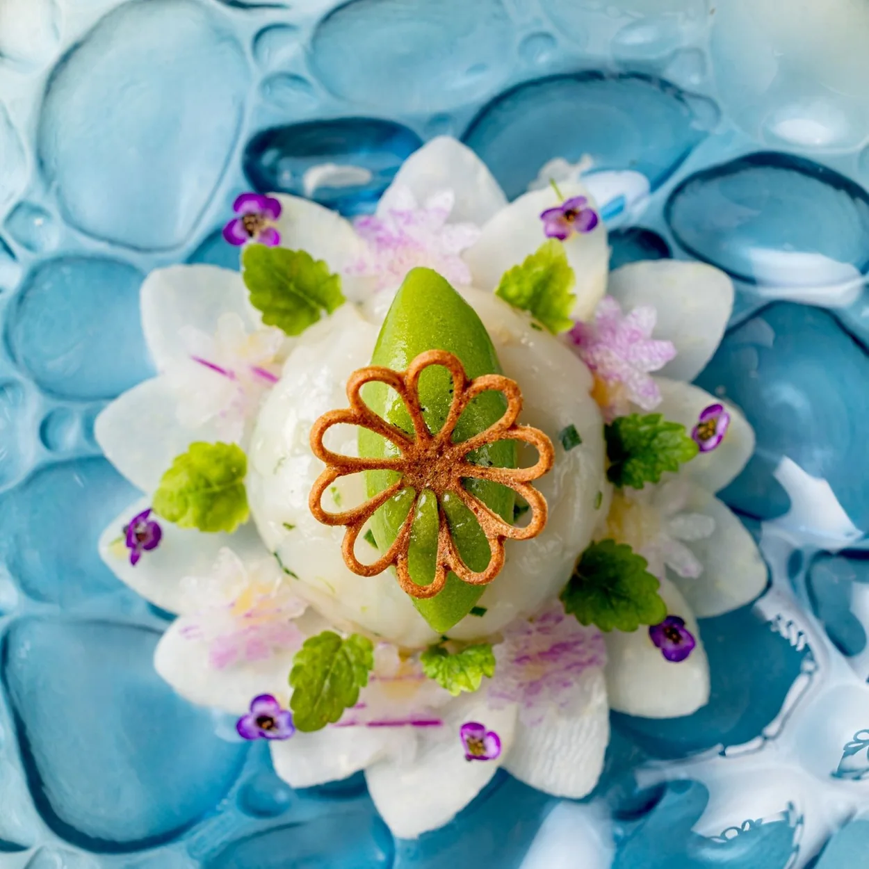 Frog by Adam Handling dish with edible flowers on a blue glass plate