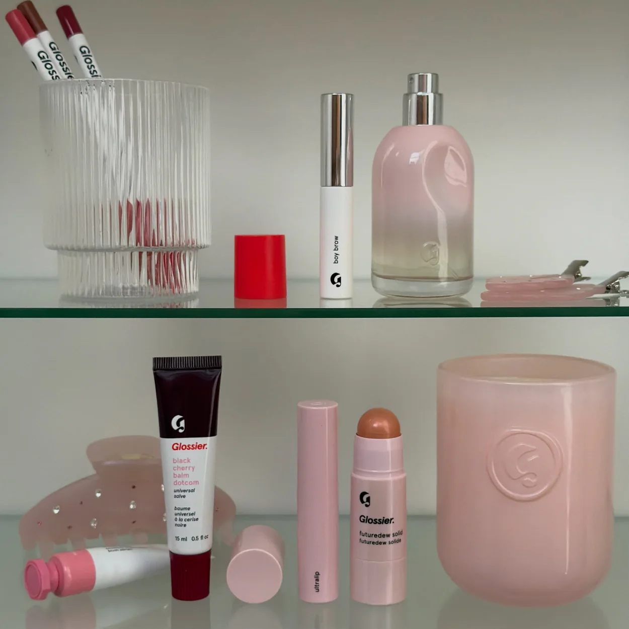 Glossier skincare and makeup products on glass shelves