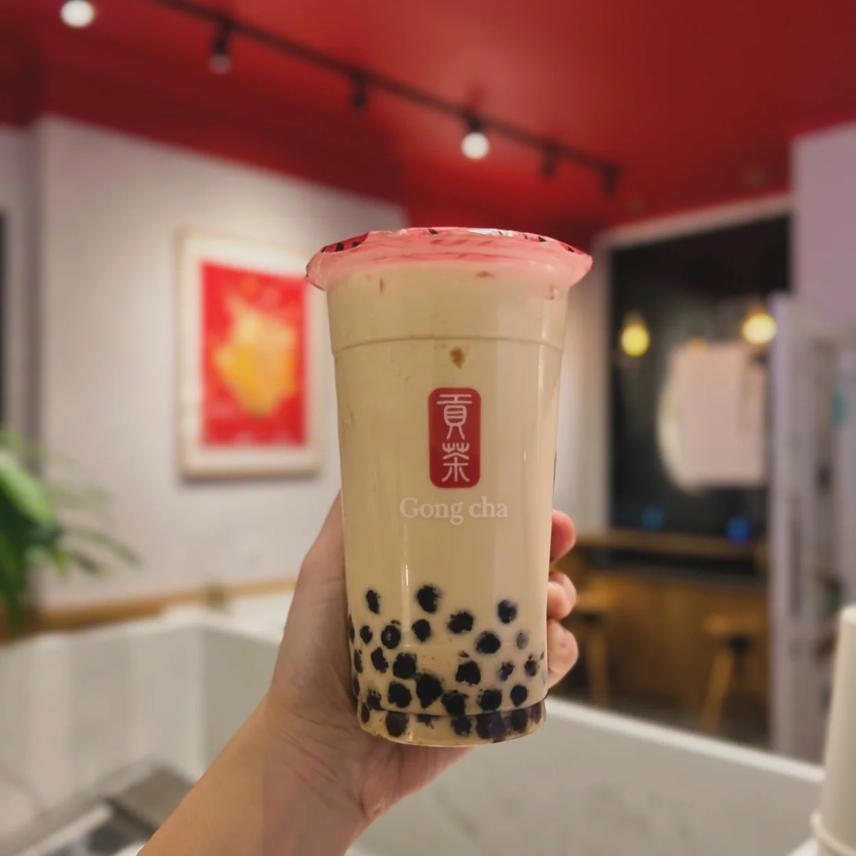 Gong Cha pearl milk tea held inside the red and white Covent Garden shop