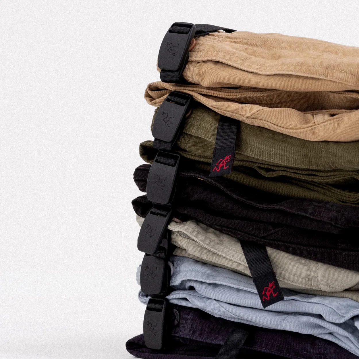 Gramicci trousers folded in a stack showing the webbing belts