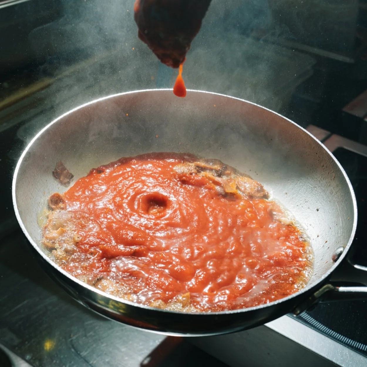 Guido's homemade tomato sauce poured into a hot pan in the open kitchen