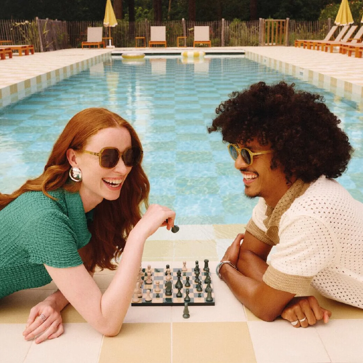 IZIPIZI sunglasses worn by a couple playing chess by a pool