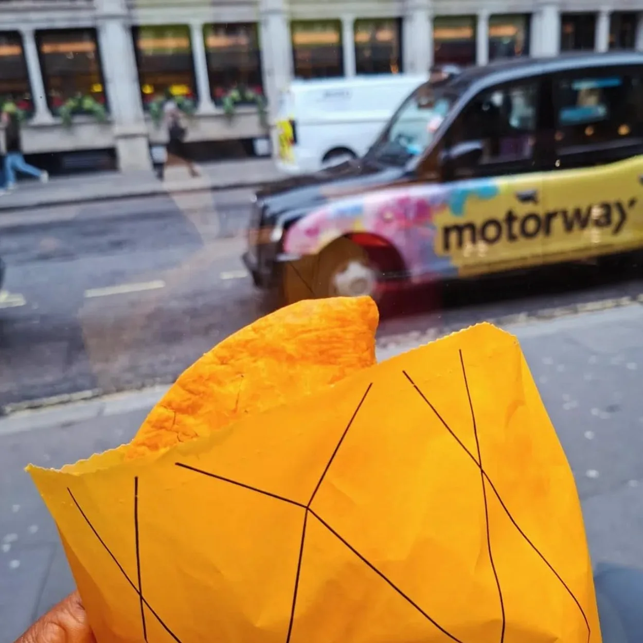 Jamaica Patty Co patty held in branded wrapper outside the shop