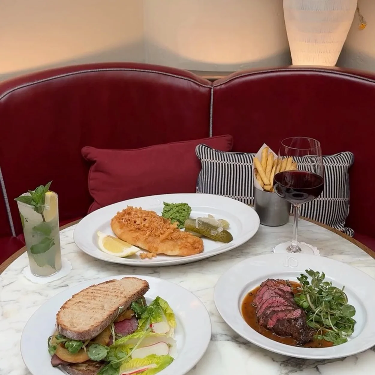 Jamie Oliver Catherine St red leather booth set with lunch plates and cocktails