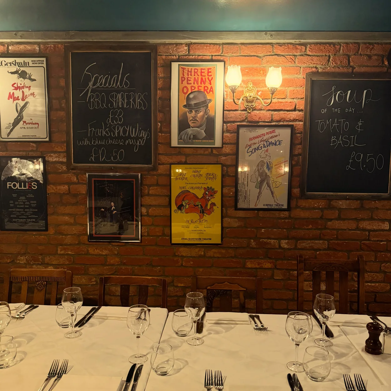 Joe Allen dining room with white tablecloths and theatre posters on exposed brick