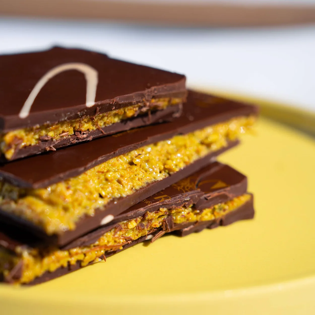 Läderach layered dark chocolate and pistachio FrischSchoggi on a yellow plate