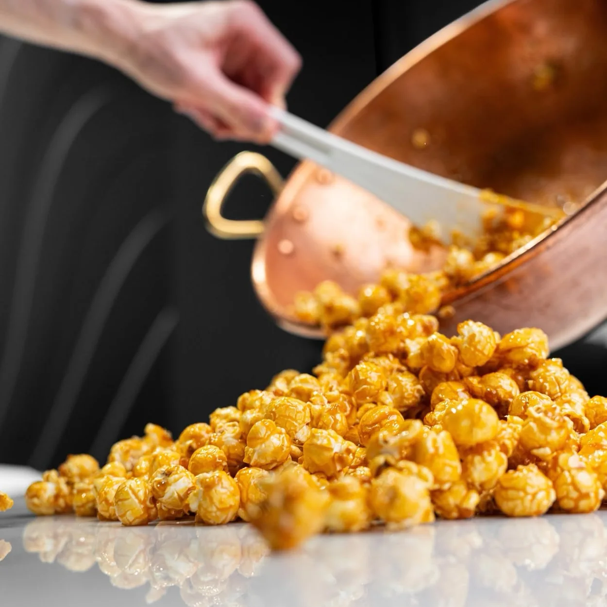 Läderach caramel popcorn poured from a copper pan