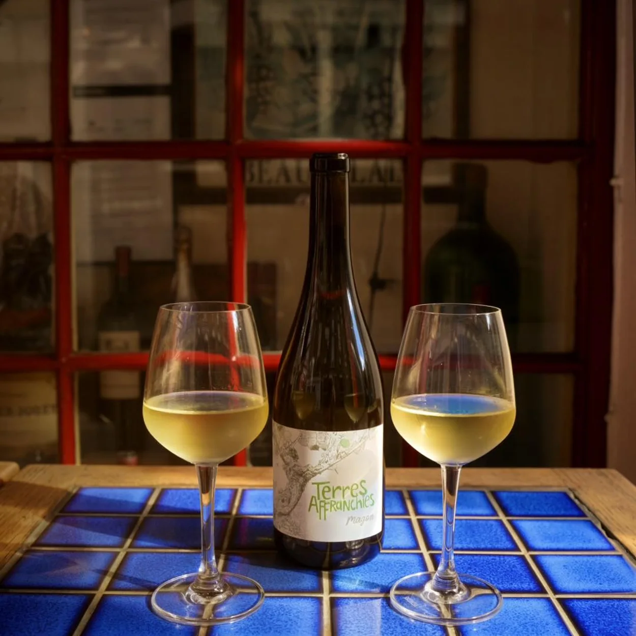 Le Beaujolais white wine poured for two by the window