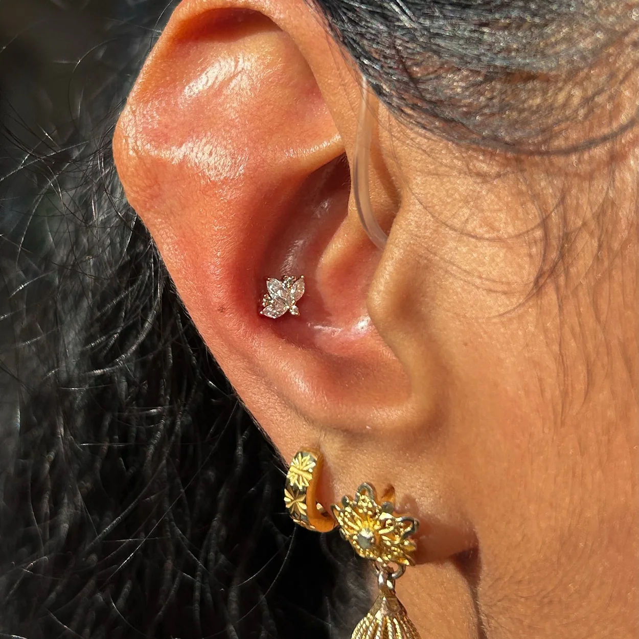 Metal Morphosis ear piercings with gold studs and drop earring