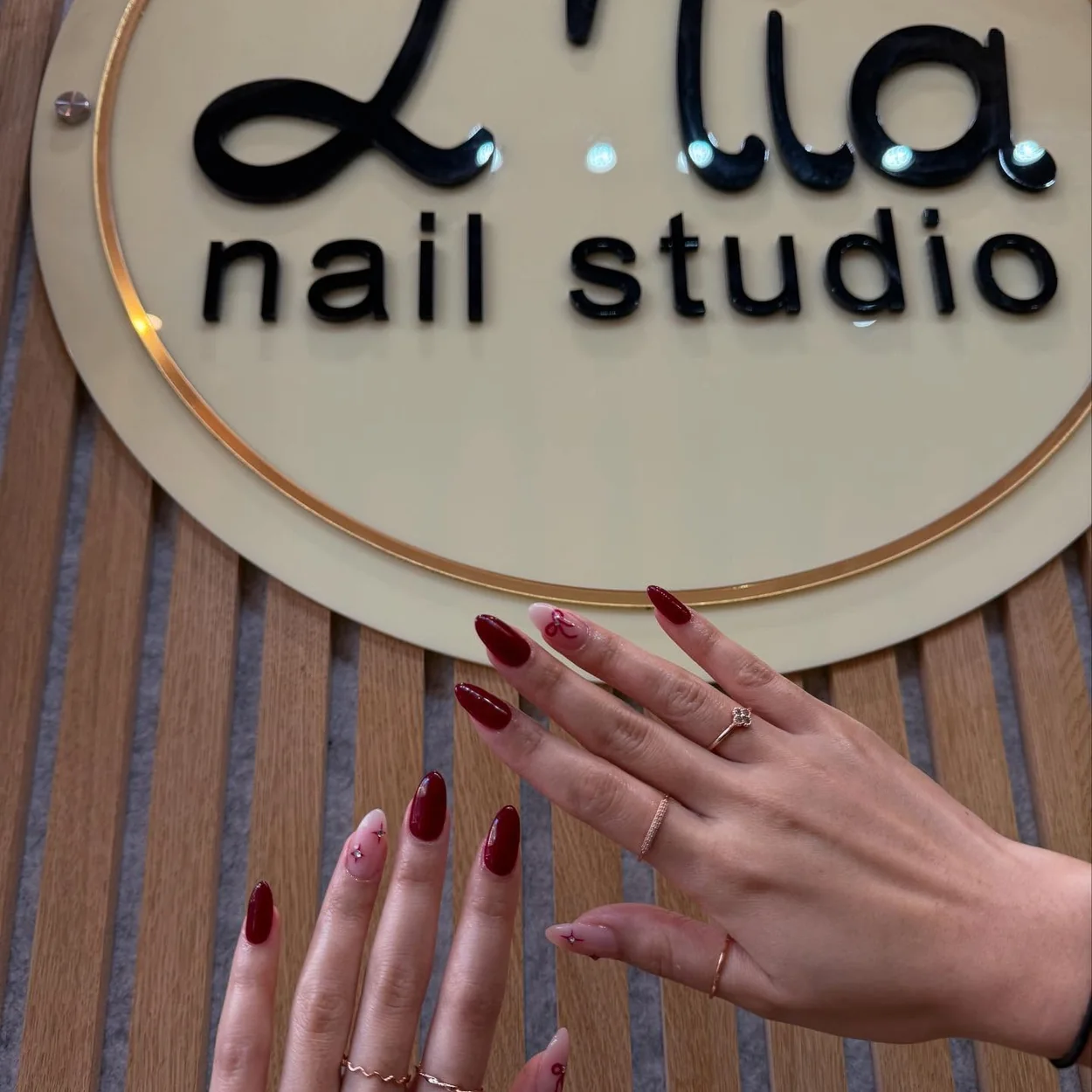 Mia Nails Covent Garden burgundy gel manicure photographed on the studio sign