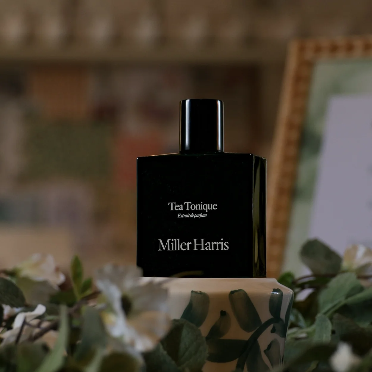 Miller Harris Tea Tonique black bottle among foliage