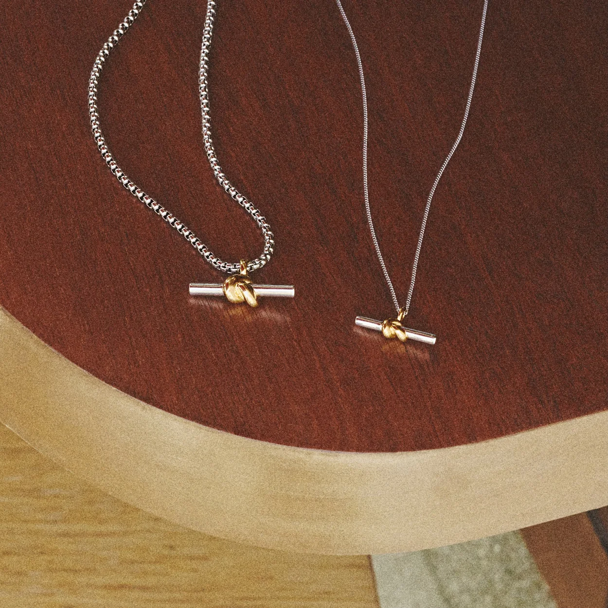 Missoma mixed metal T-bar pendant necklaces on a wooden surface