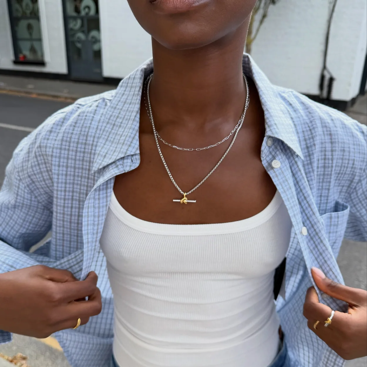 Missoma layered chain necklaces worn with a white vest and shirt
